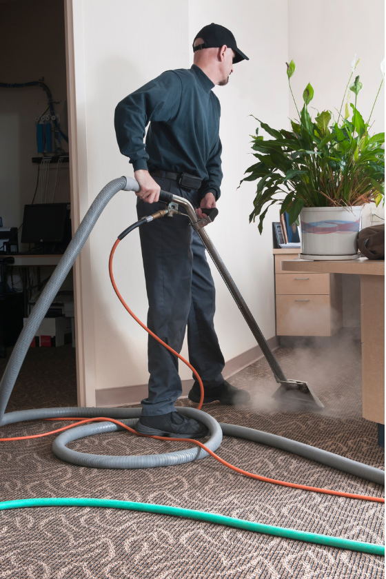 A man is cleaning a carpet with a vacuum cleaner.