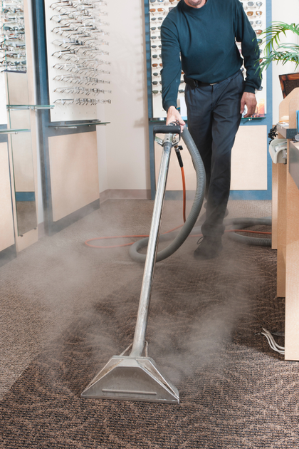 A man is using a vacuum cleaner to clean a carpet in an office.