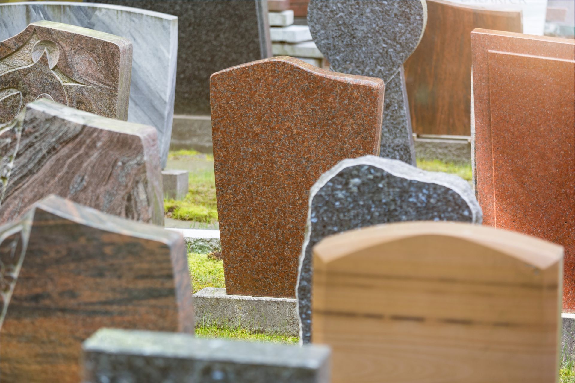 Assorted granite headstones in varied colors and shapes on display at a monument studio