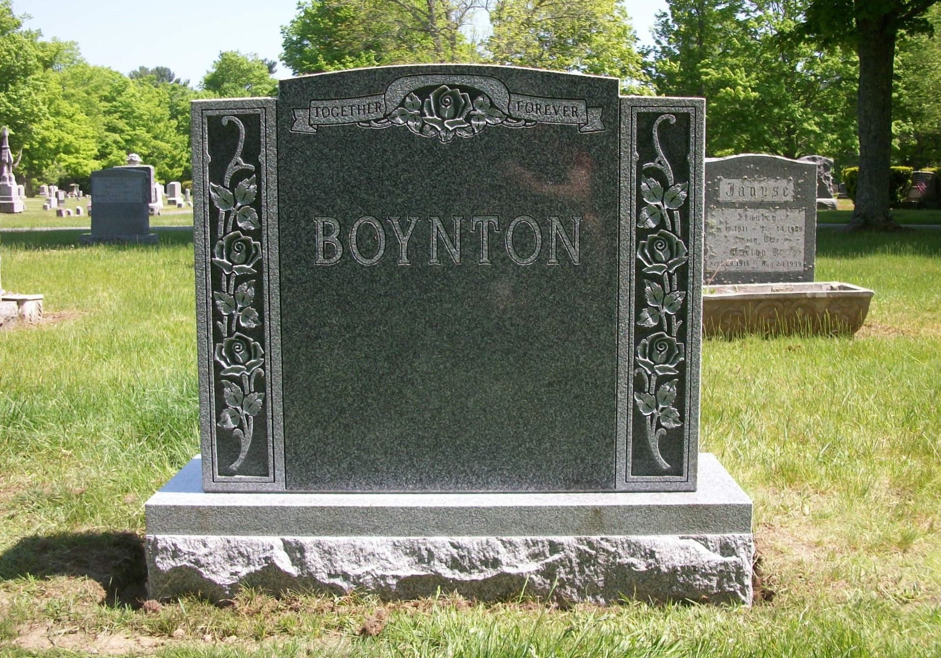 A polished dark granite tombstone engraved with the name 