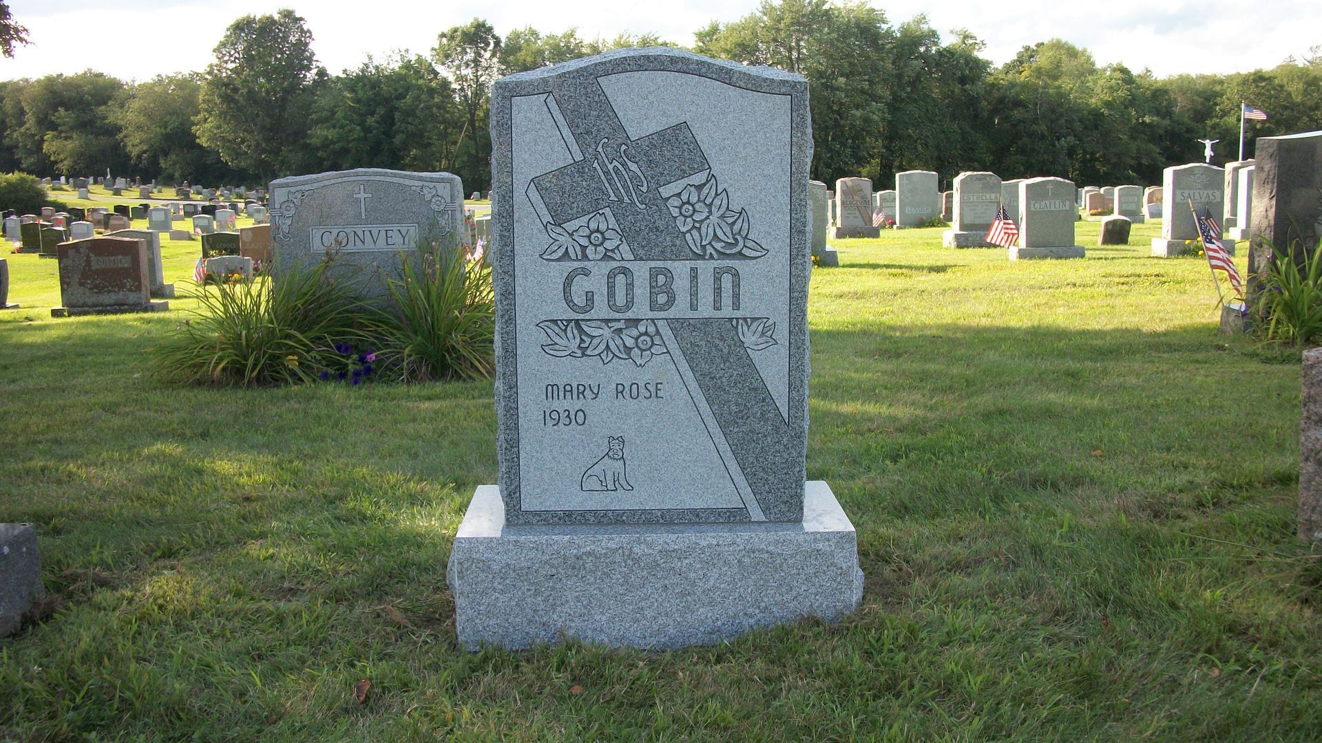 A gray granite tombstone with a cross engraving, labeled 