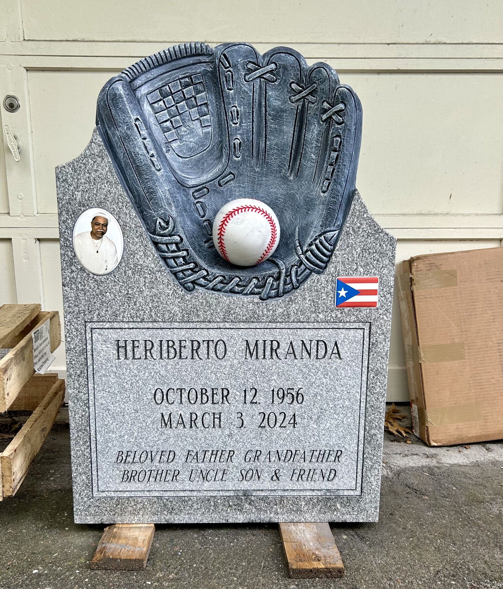 A gravestone featuring a sculpted baseball glove and ball, a photo, and a Puerto Rican flag for Heriberto Miranda.