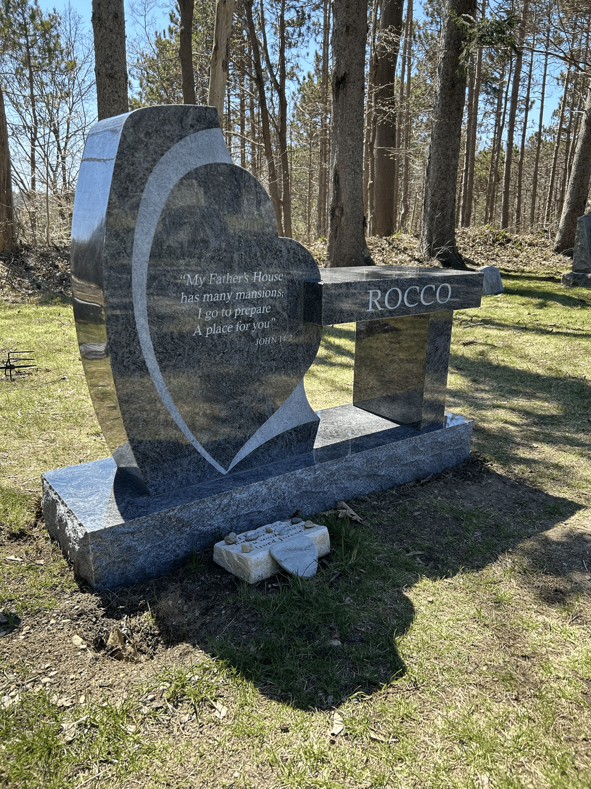 A granite tombstone featuring a heart-shaped monument and an attached bench engraved with the name 