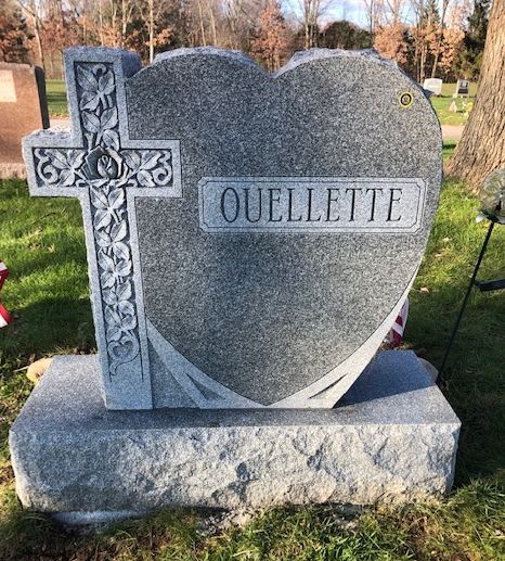 A heart-shaped gray granite headstone inscribed with 