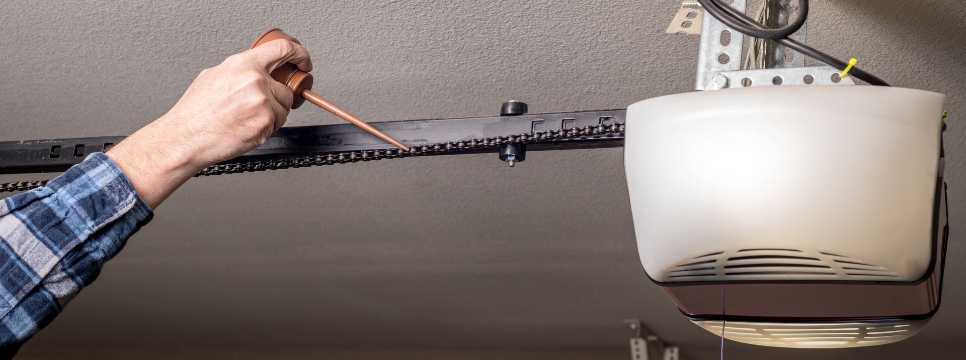 A man oiling a garage door chain