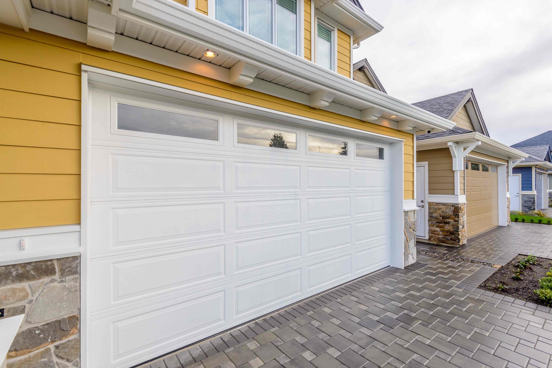 A white garage door against yellow house siding