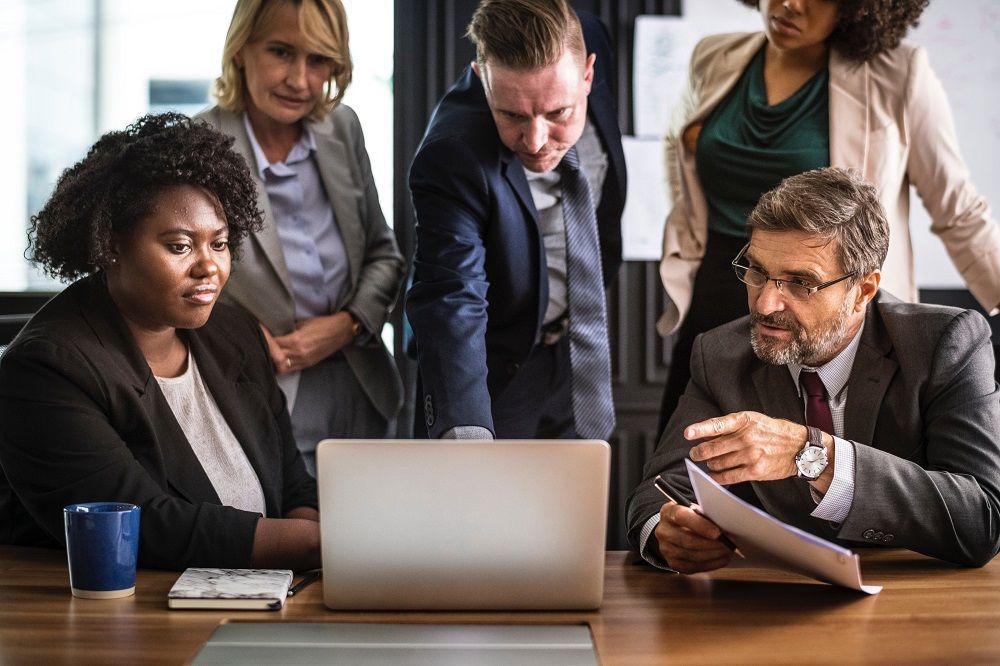 A group of business people are looking at a laptop computer.
