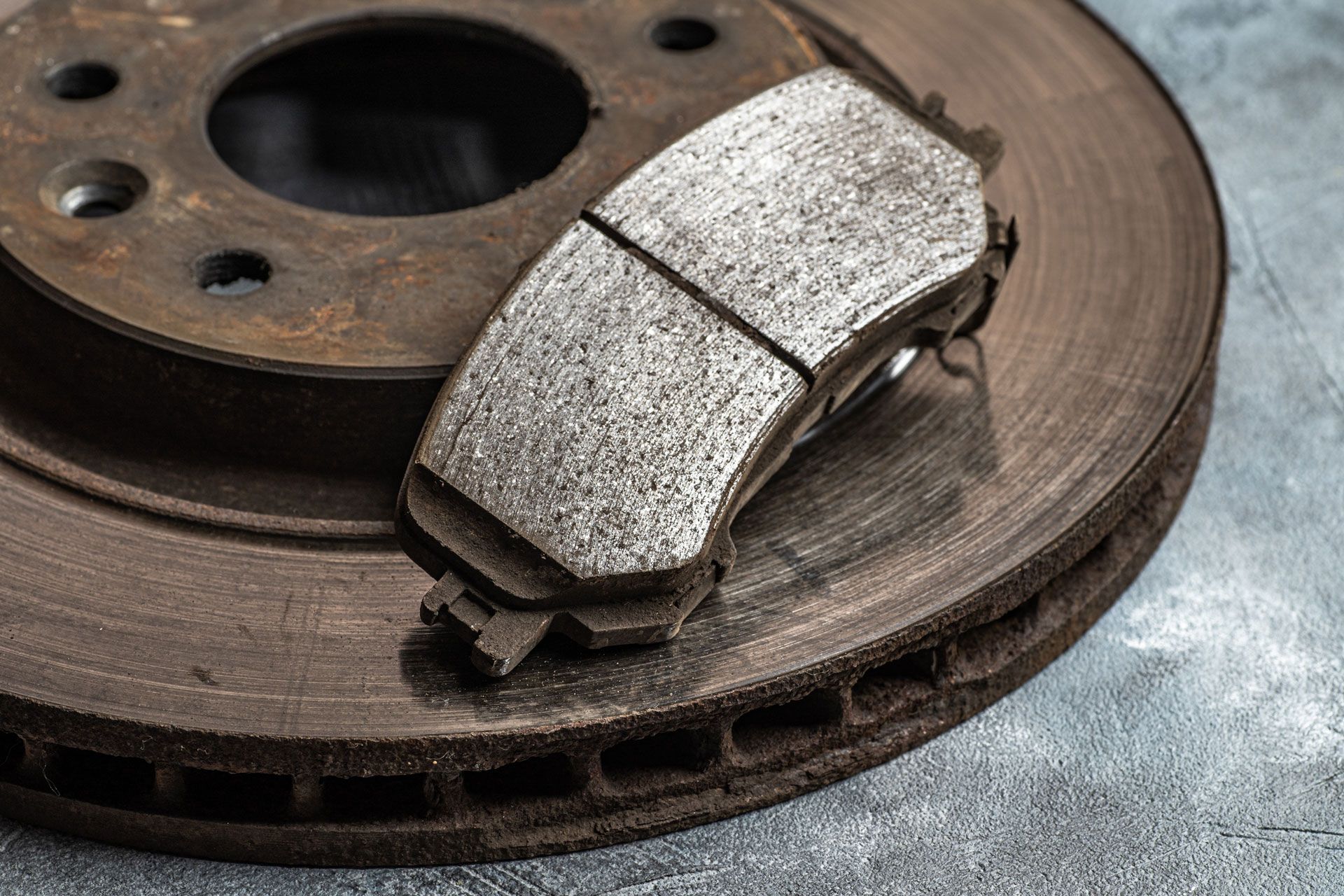 Brake rotor and worn brake pads, showing rust, with a close-up view.