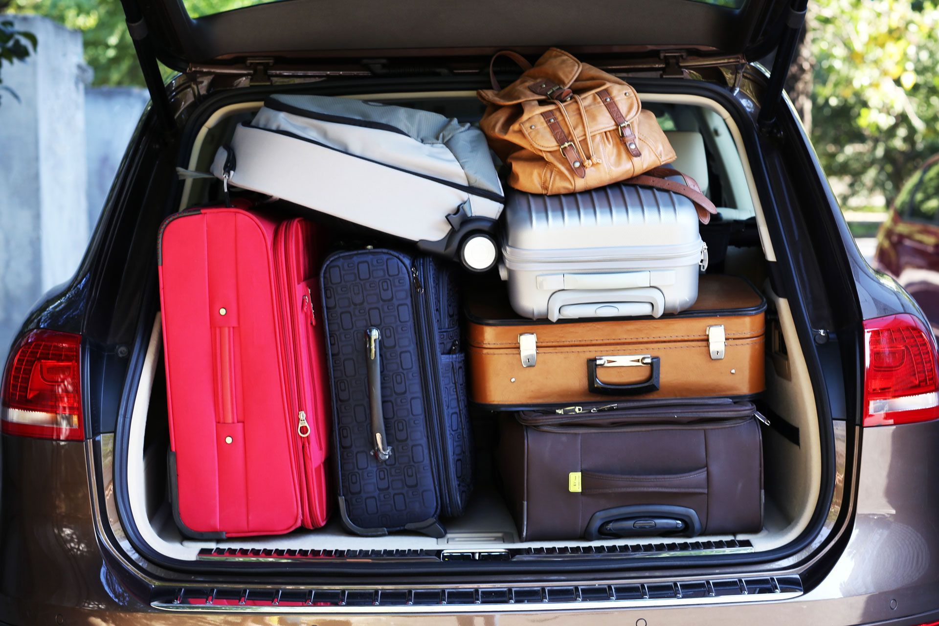 Car trunk filled with various suitcases, ready for travel.