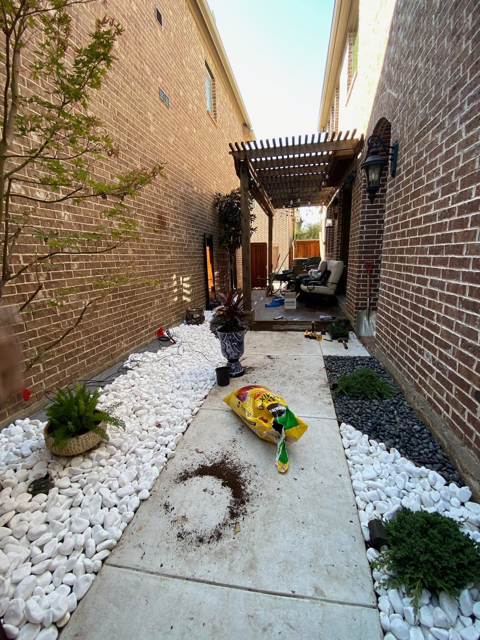 Narrow brick alley with a concrete path, white gravel, and a yellow toy truck in the foreground