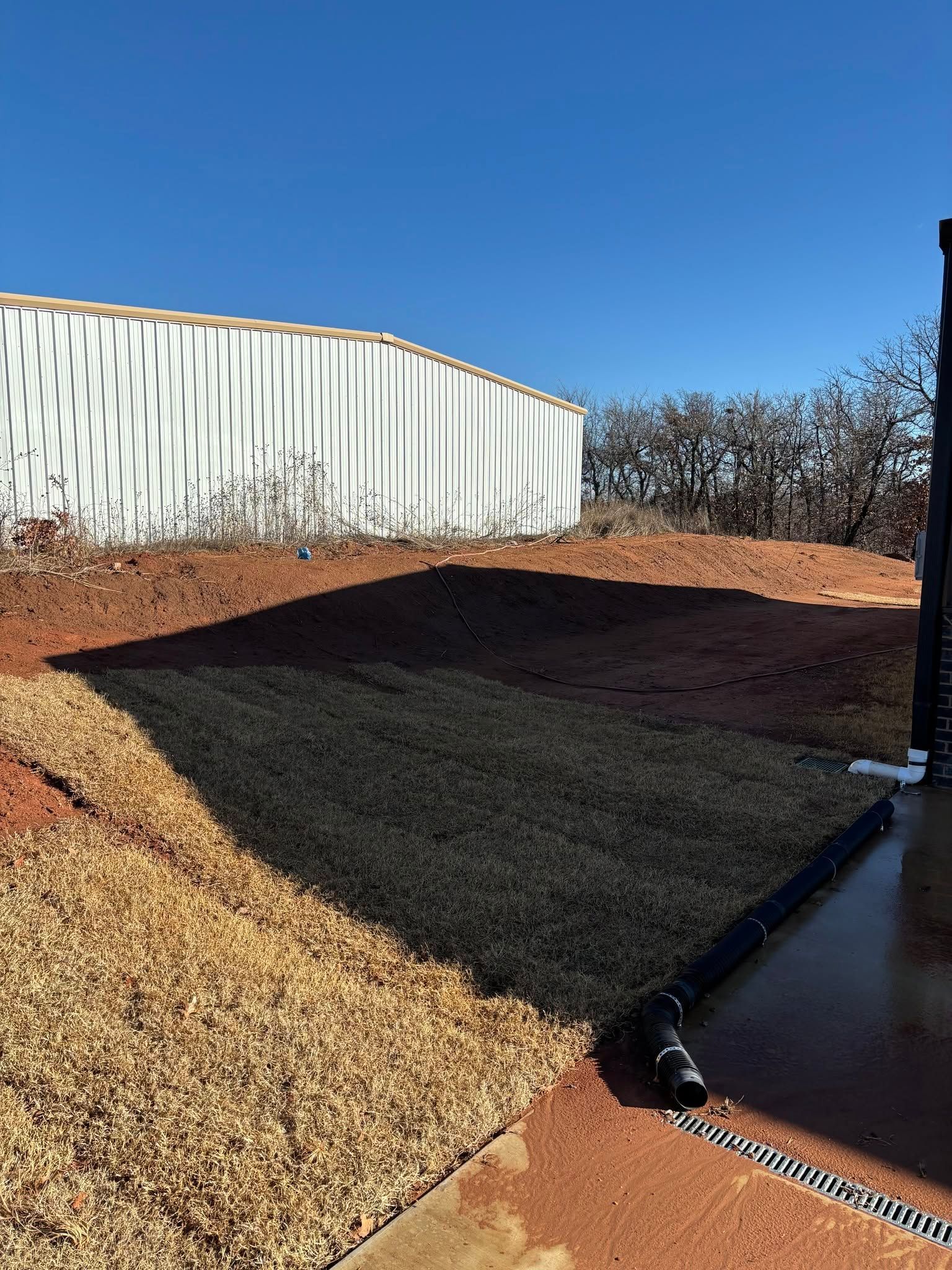 Mulched landscape beside a white metal building under a clear blue sky