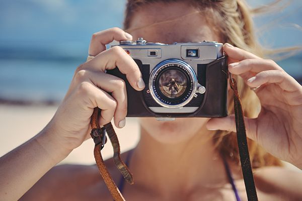 a woman is taking a picture with a camera on the beach .