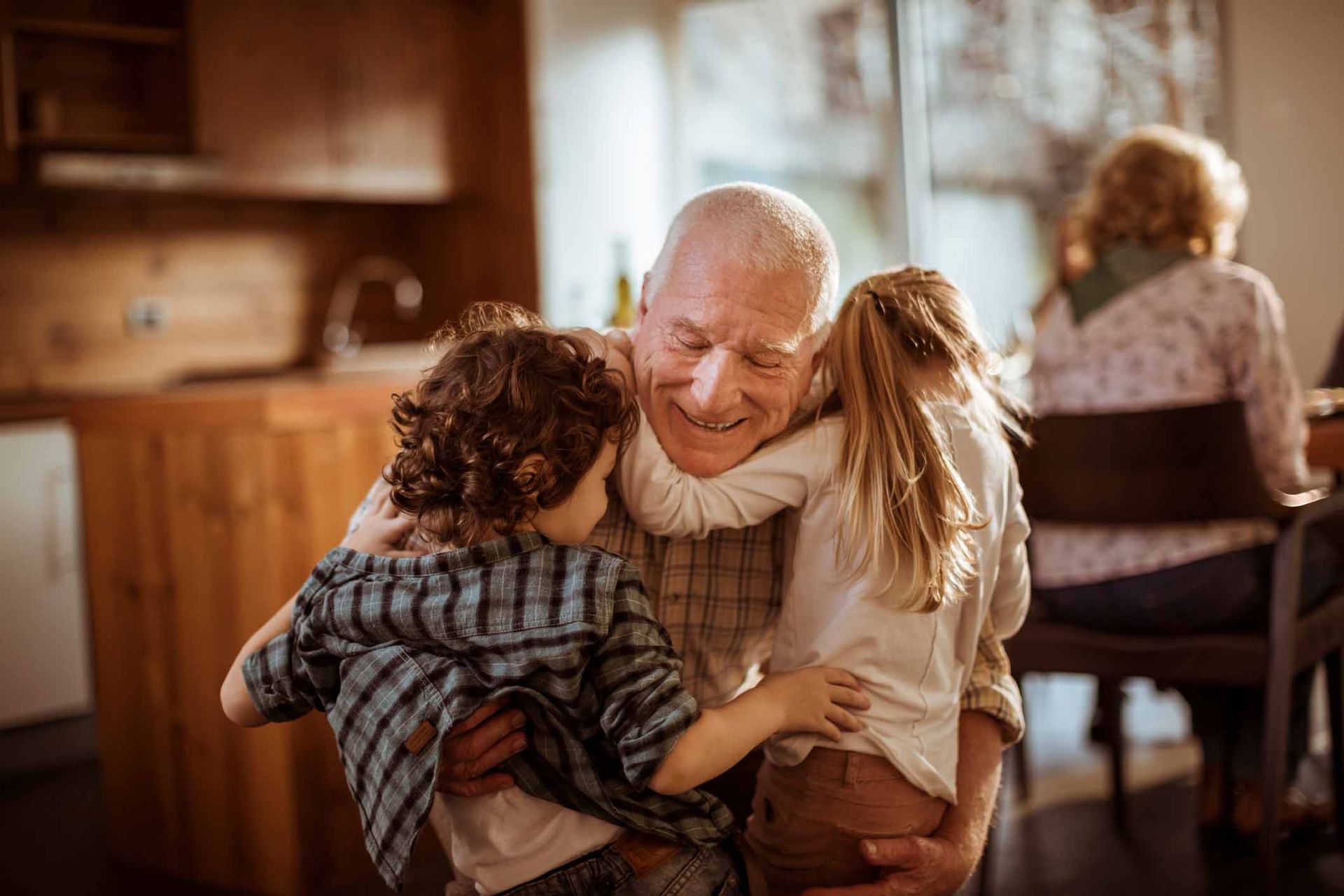 an elderly man is holding two children in his arms .