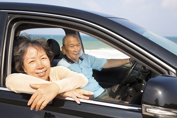 an elderly couple is sitting in a car on the beach .