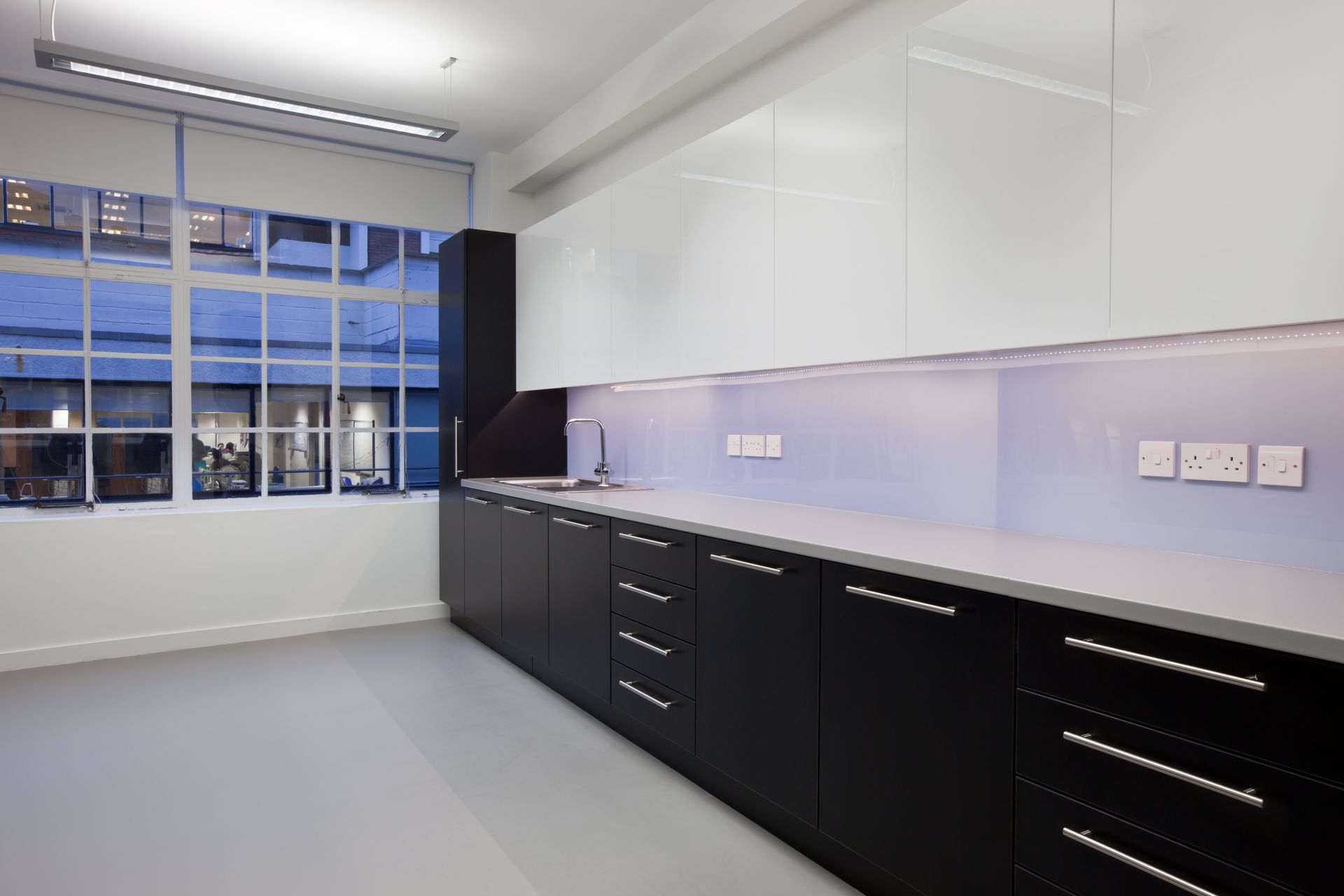 An empty kitchen with black cabinets and white counter tops
