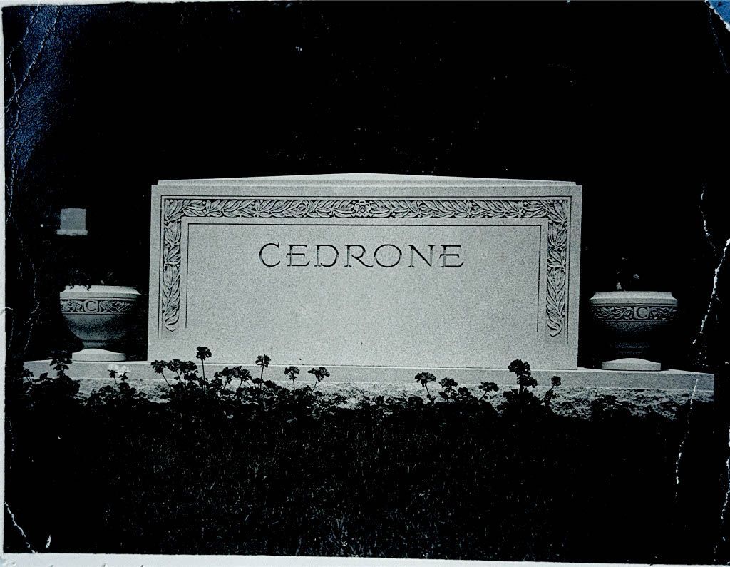 Carved stone memorial plaque with flowers in front against a dark background