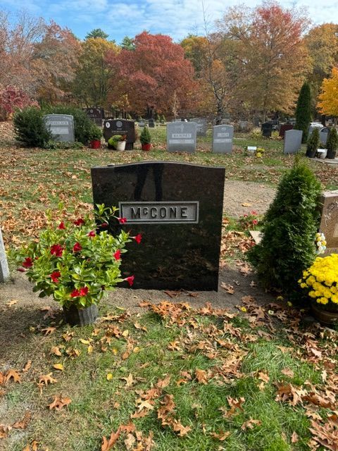 McCone gravestone with flowers in a cemetery, surrounded by autumn trees and fallen leaves