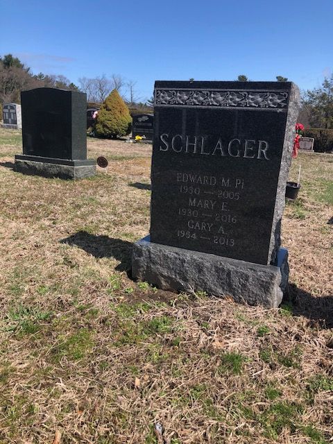 Two gravestones in a grassy cemetery, one large black Schlager headstone in the foreground