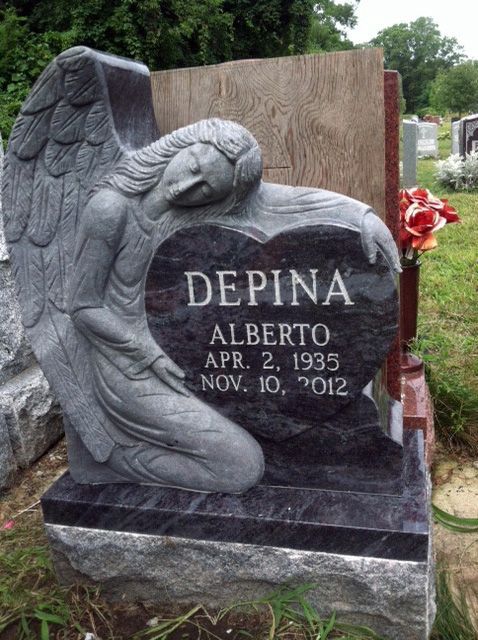 Angel kneeling beside a gravestone engraved “DEPINA ALBERTO APR. 2, 1935 NOV. 10, 2012”