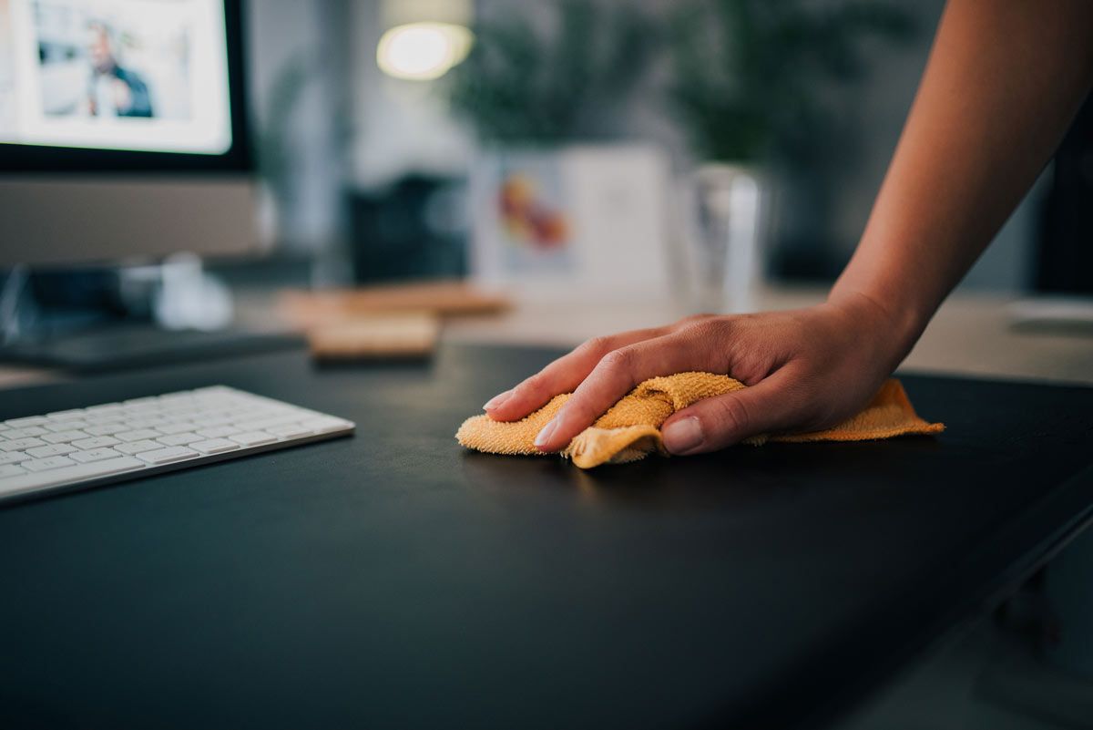 A person is cleaning a desk with a cloth