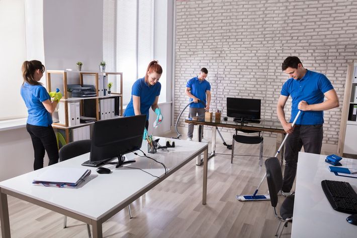 A man is cleaning a desk with a computer on it A man is cleaning a desk with a computer on it