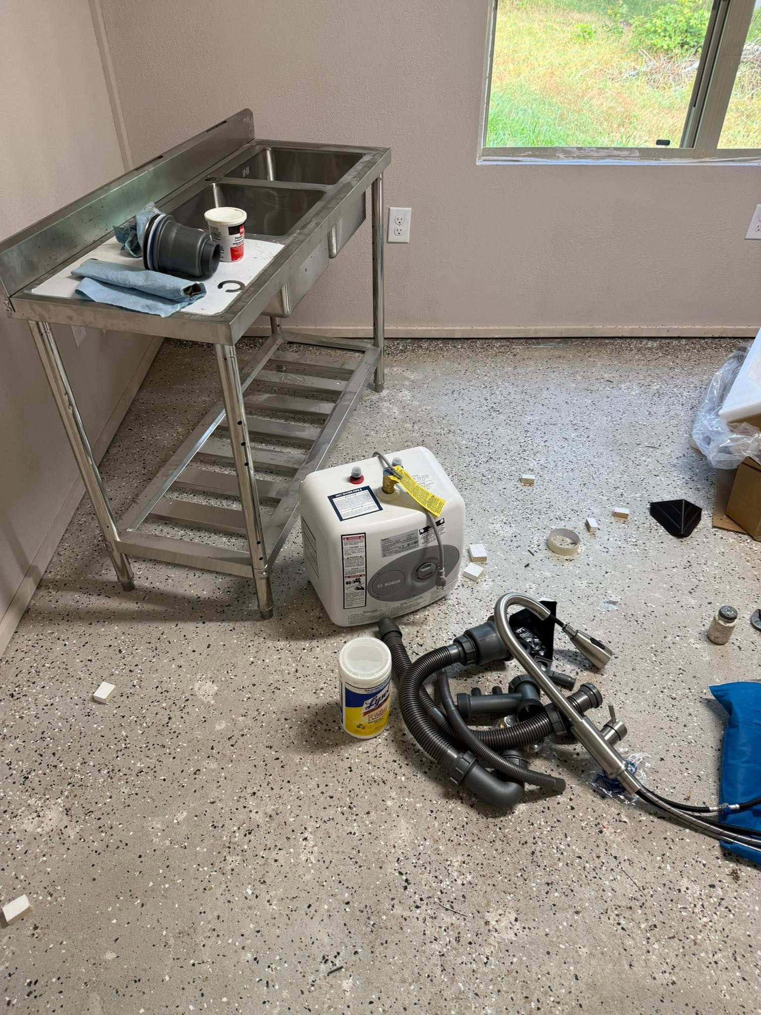 Messy room with a metal sink, scattered debris, and a floor-cleaning machine on the floor