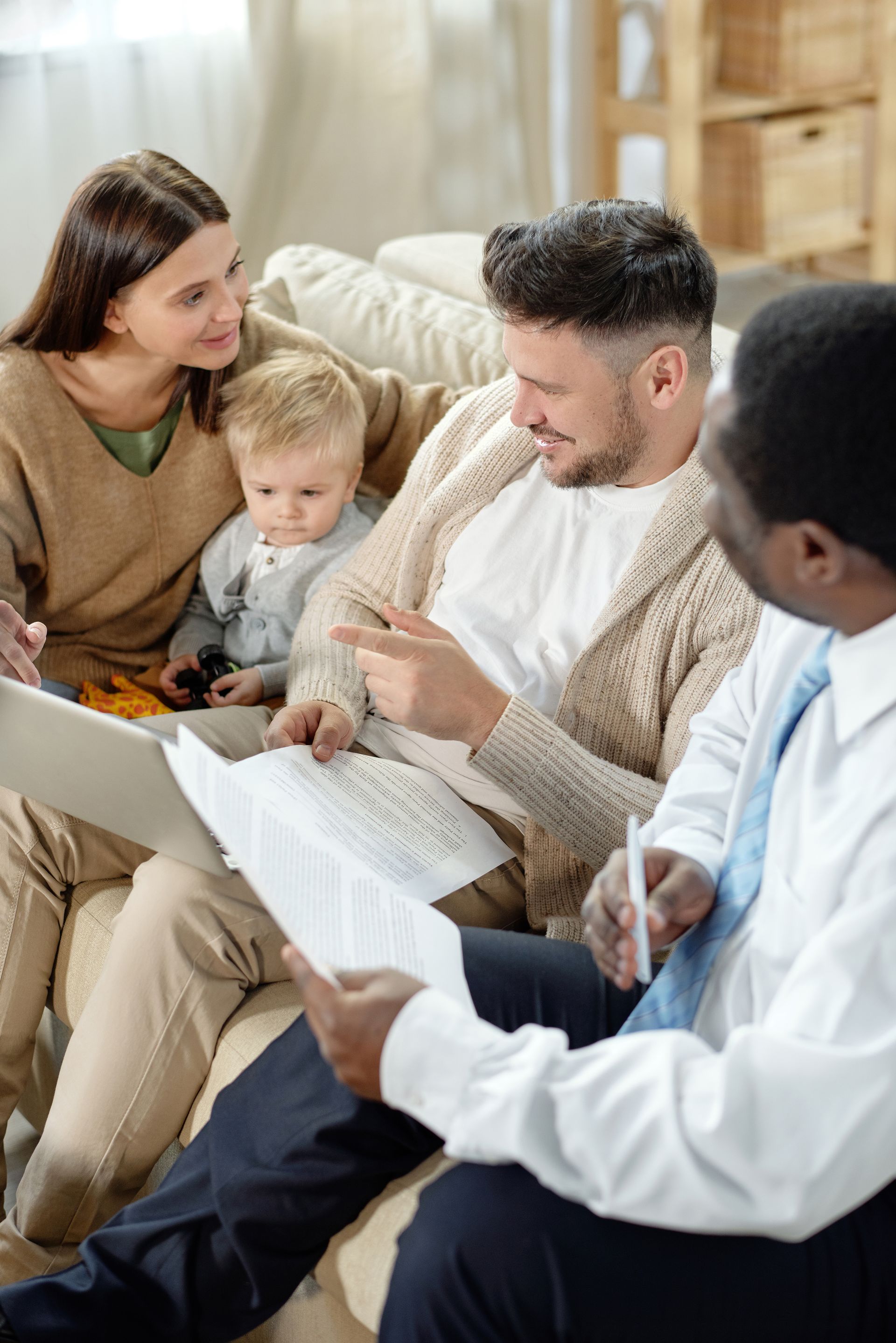 Family with a child and advisor reviewing documents on a couch indoors.