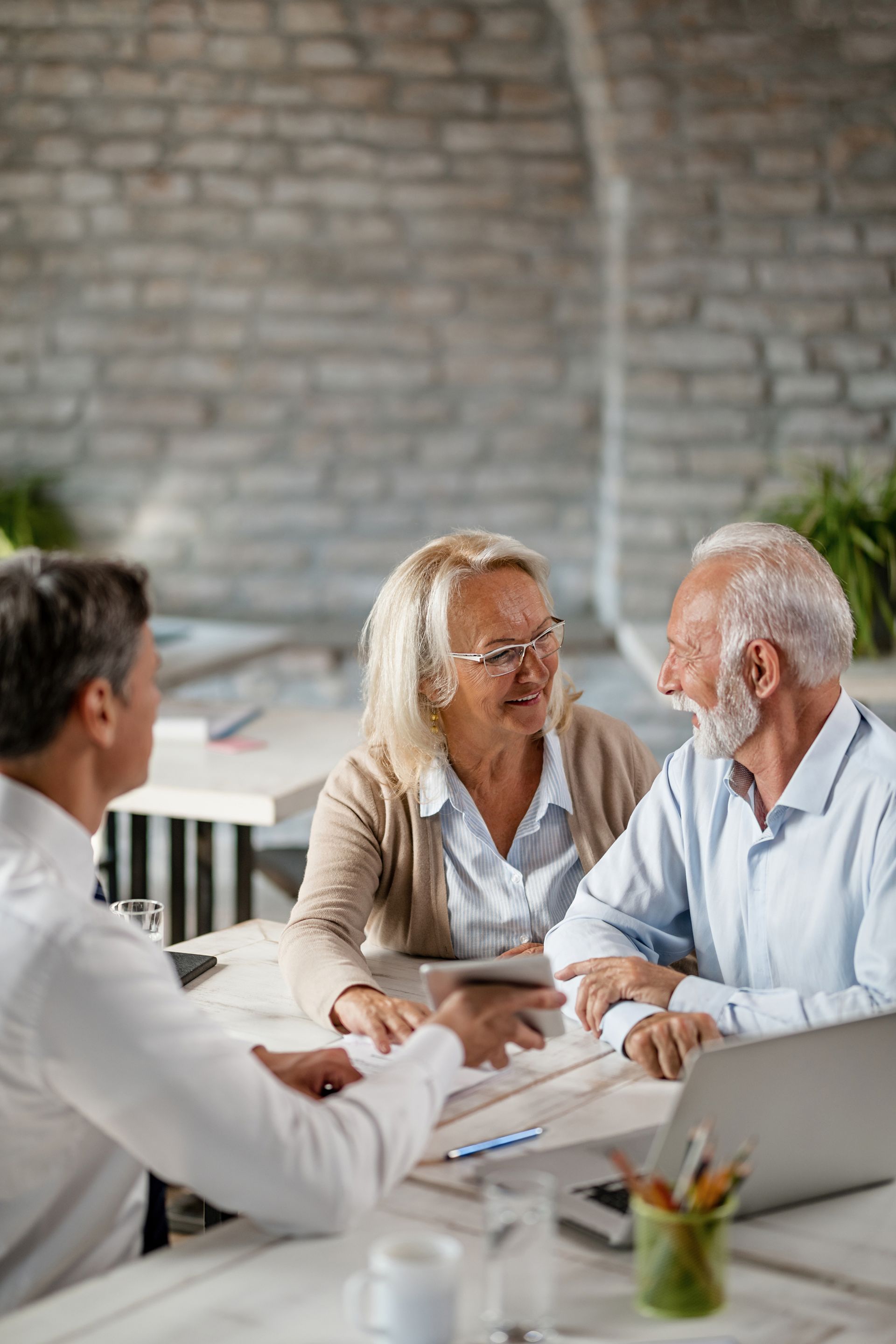 A financial advisor showing documents to an elderly couple at a table.