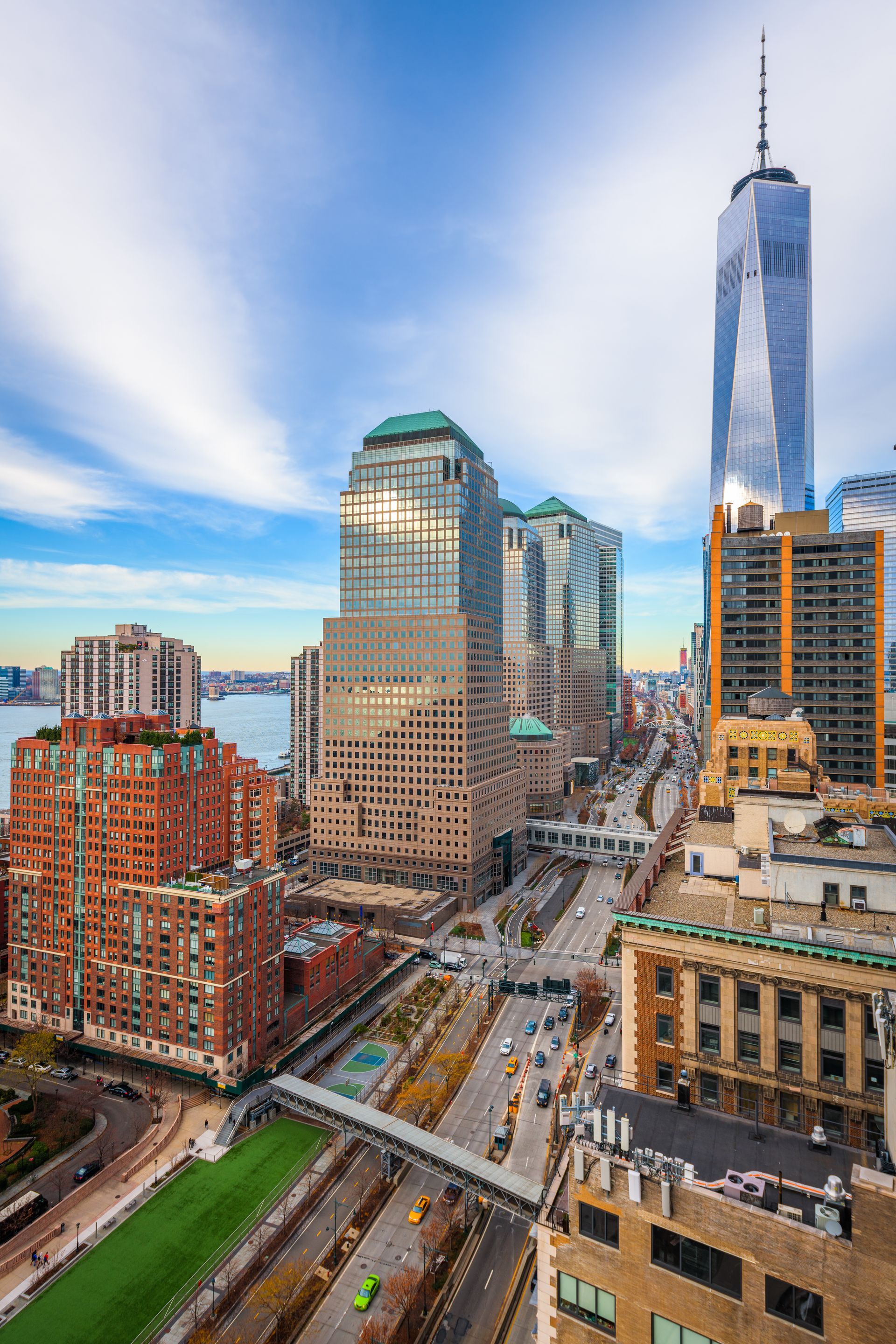 New York City skyline with skyscrapers and roadway under a blue and cloudy sky.