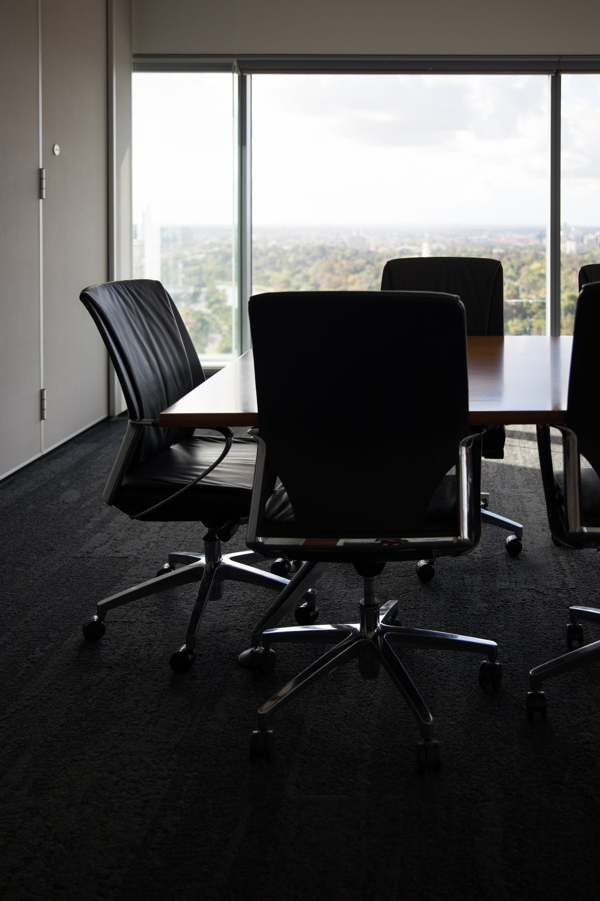 Conference room with leather chairs and a table, a large window provides a view of a city.