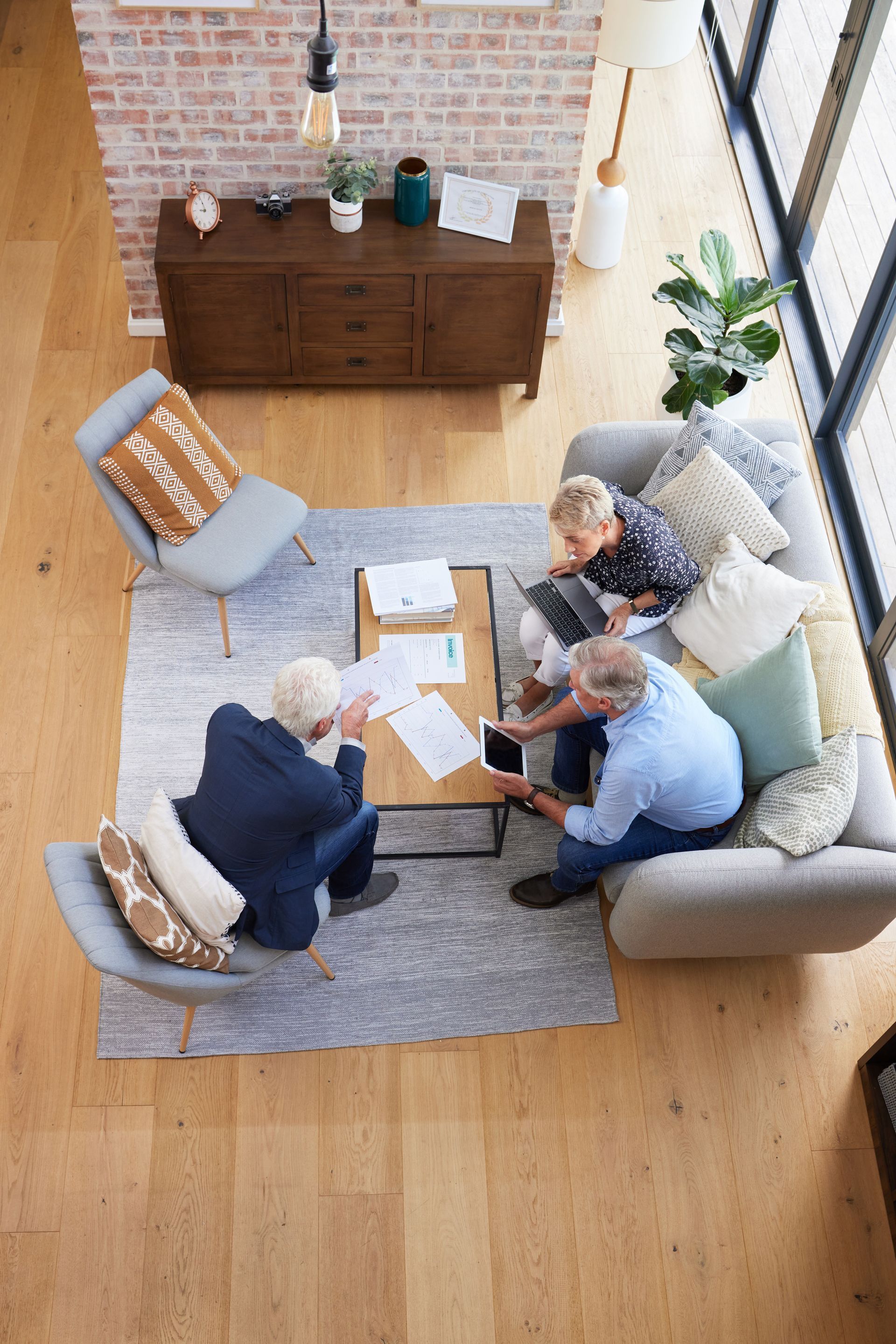 Three people reviewing documents around a coffee table in a living room.