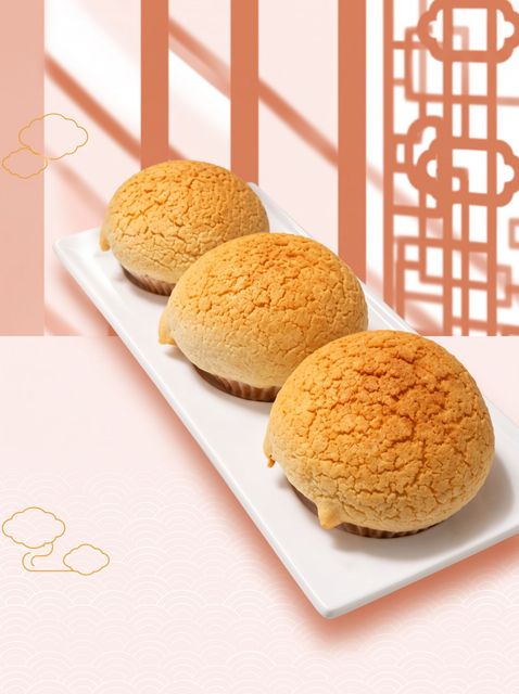 Three golden buns on a white rectangular plate against a pink patterned background