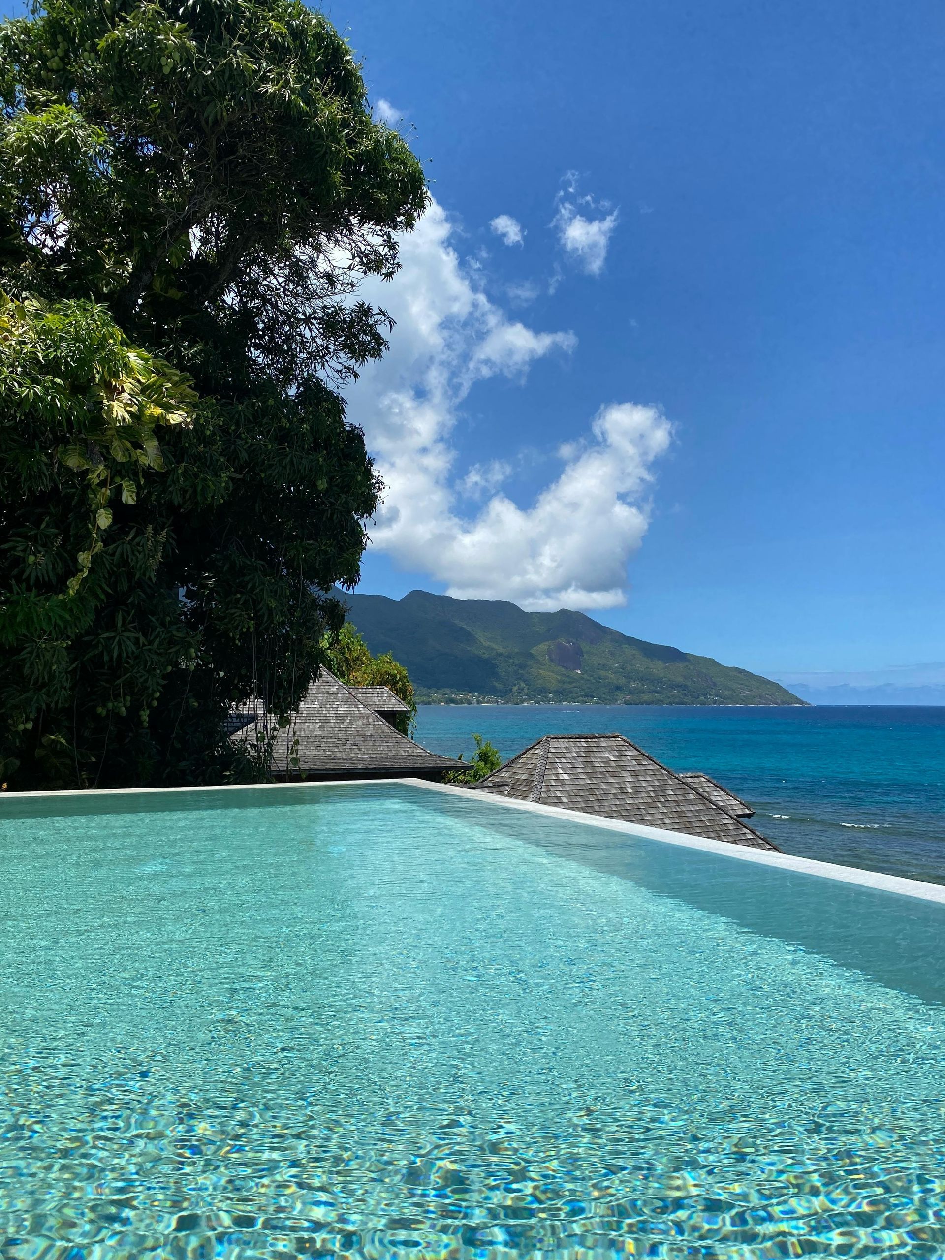 A swimming pool with a view of the ocean and mountains in the background.