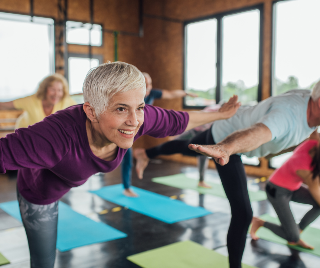 A group of people are doing yoga together in a gym.
