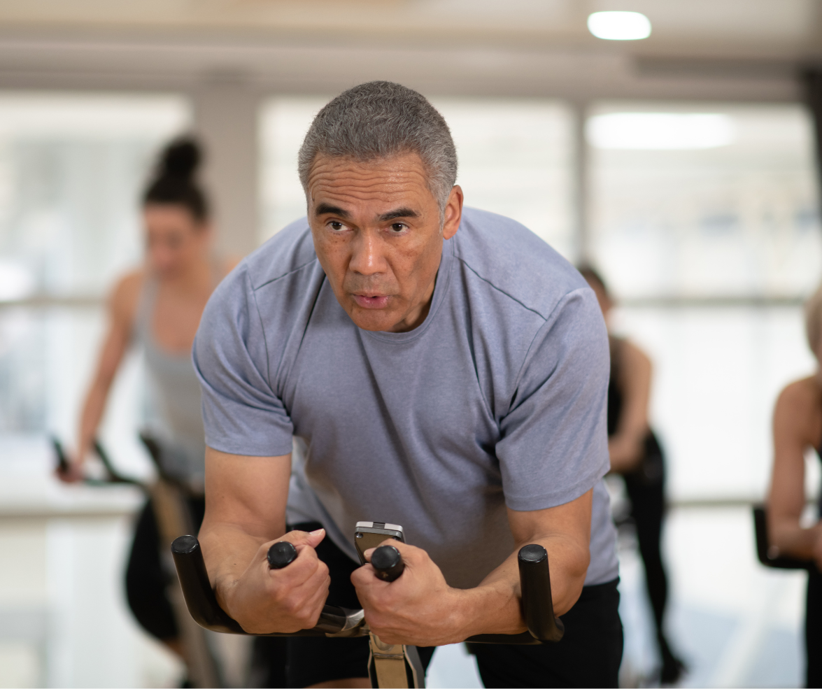 A man is riding an exercise bike in a gym.