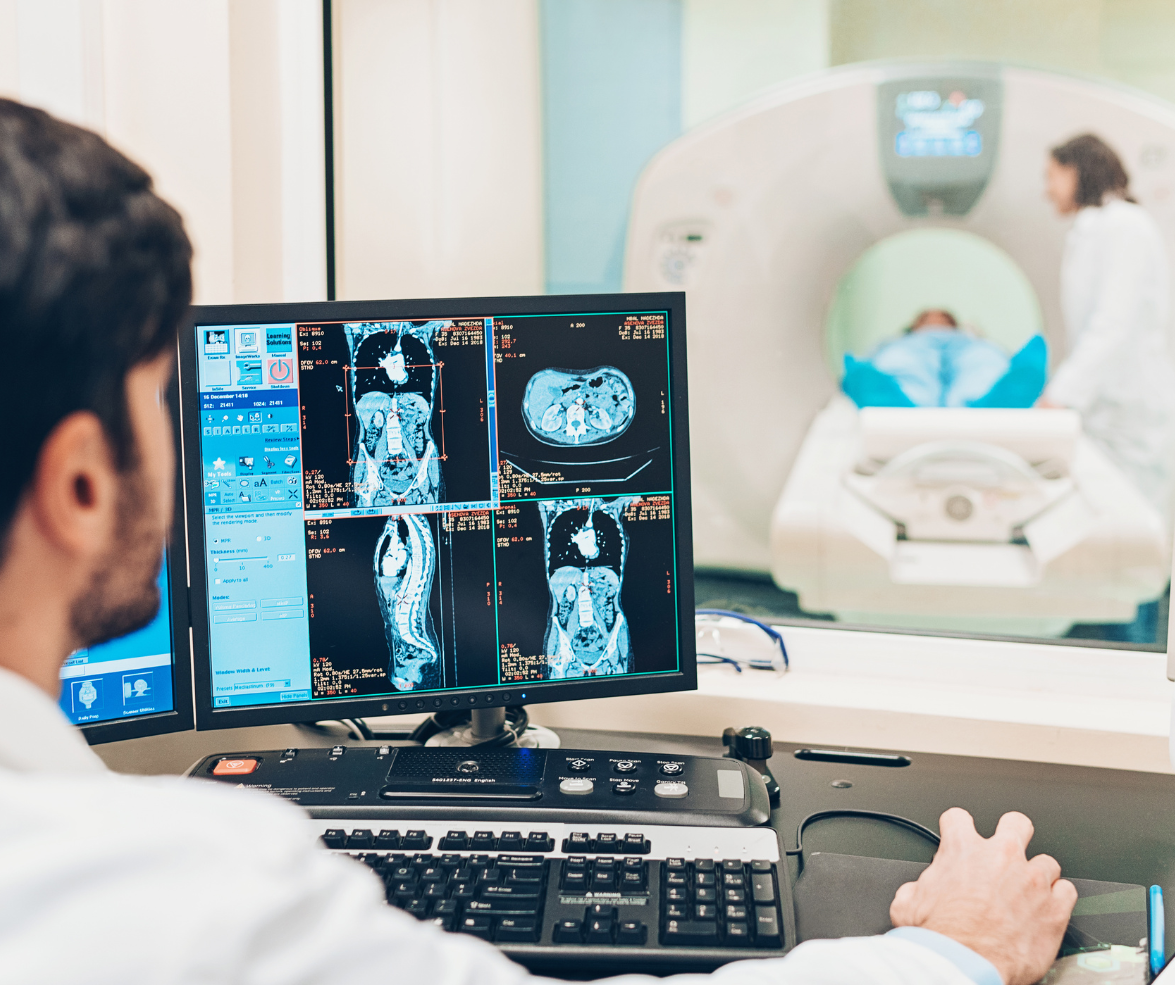 A man in a lab coat is looking at a computer screen.