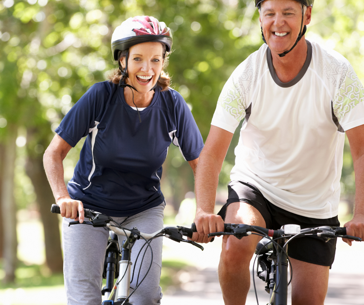 A man and a woman are riding bicycles together and smiling