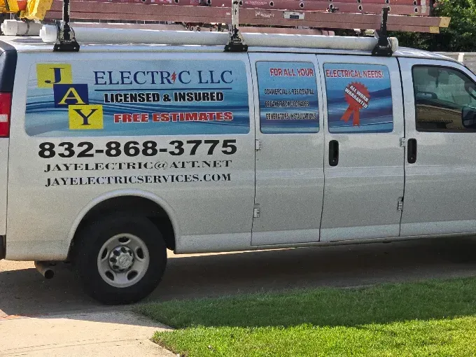 White Electric LLC service van with ladder on top, parked outside with company name and phone number on the side.
