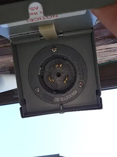 Close-up of a recessed ceiling electrical outlet or light fixture with a dark circular socket and cover.
