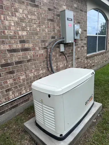 Outdoor generator unit beside a brick building, with utility connections and a window nearby.