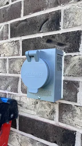 Blue outdoor electrical outlet box mounted on a brick wall