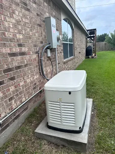 Outdoor generator beside a brick house, sitting on a concrete pad along a grassy side yard.