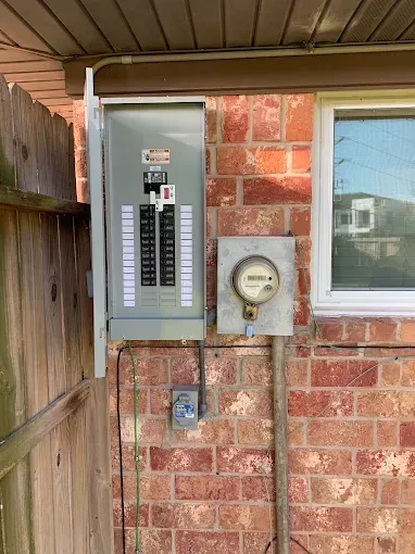 House exterior with electrical breaker panel, meter, and window on a brick wall