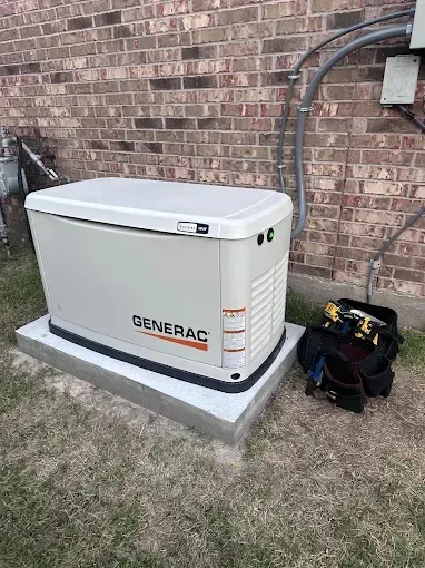 Generac home backup generator on a concrete pad beside a brick house with tools nearby