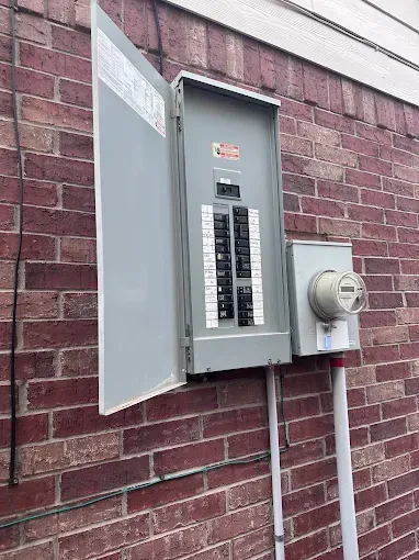 Open electrical breaker panel mounted on a brick exterior wall