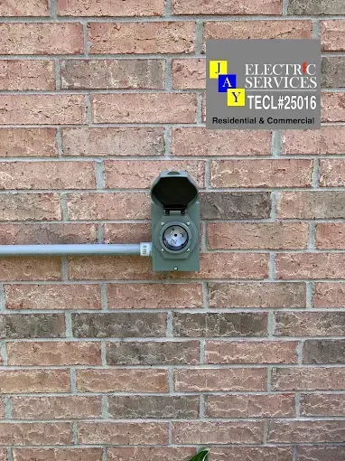 Brick wall with an electric service meter box and a sign for J&J Electric Services