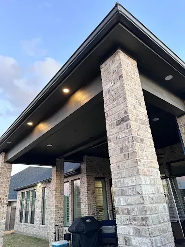 Modern covered porch with stone columns and dark ceiling, viewed from below