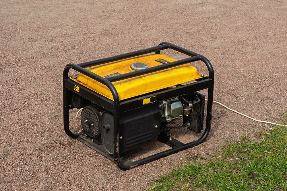 Portable yellow and black generator on a driveway with a power cord attached