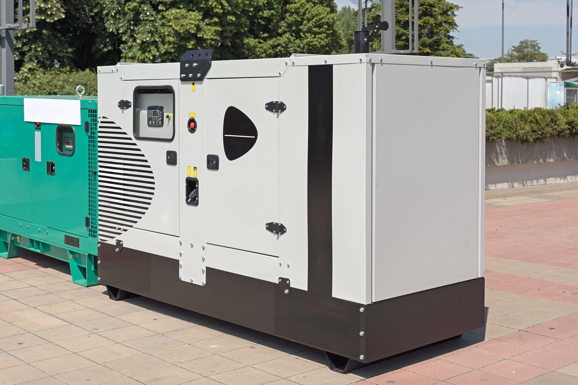 White and teal industrial generator unit parked outdoors on a paved surface