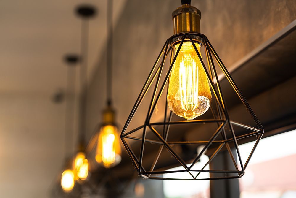 Warm hanging pendant lights with black wire cages in a softly blurred interior hallway